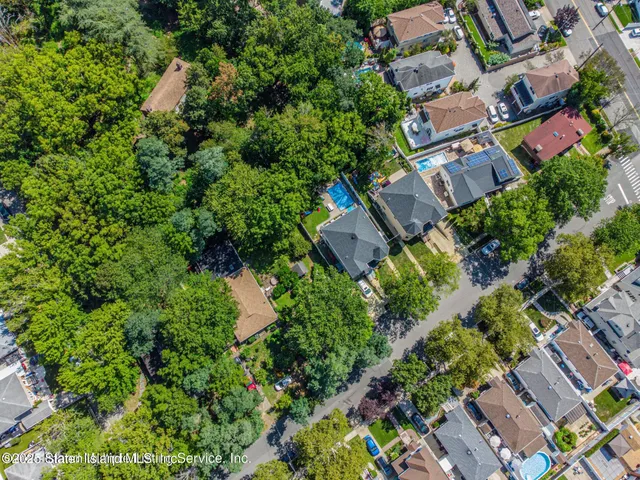 an aerial view of house and yard with swimming pool and trees