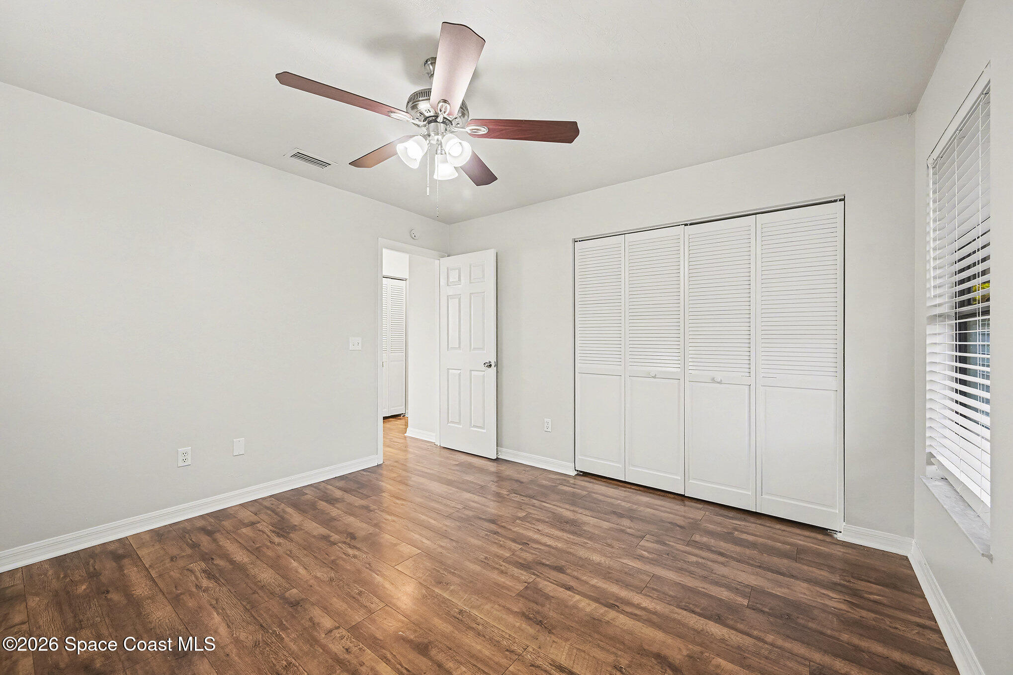 110 Cardinal Drive Sebastian, FL 32958 - Photo 13 of 23 an empty room with wooden floor fan and windows