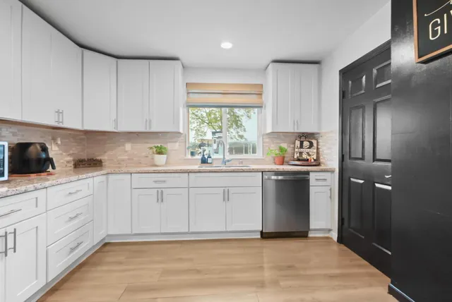 a kitchen with granite countertop white cabinets and white stainless steel appliances