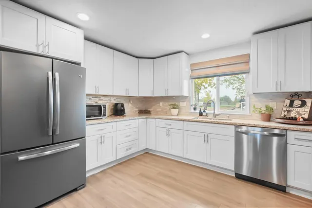 a large kitchen with stainless steel appliances kitchen island granite countertop a table chairs sink and cabinets