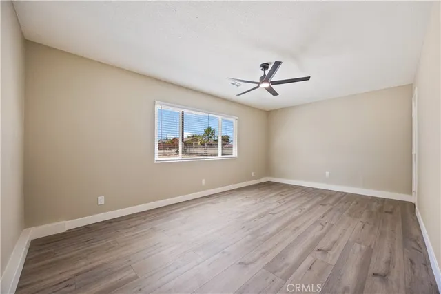 an empty room with wooden floor and ceiling fan