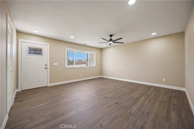 a view of an empty room with wooden floor and a window