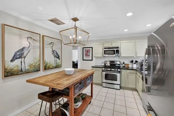 a kitchen with stainless steel appliances granite countertop a stove top oven a sink dishwasher a dining table and chairs with wooden floor