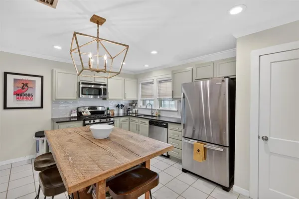 a kitchen with stainless steel appliances granite countertop a refrigerator a stove a sink a dining table and chairs with wooden floor