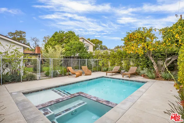 a view of a backyard with swimming pool and sitting area