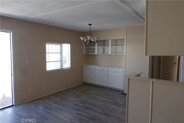 an empty room with wooden floor fireplace and windows