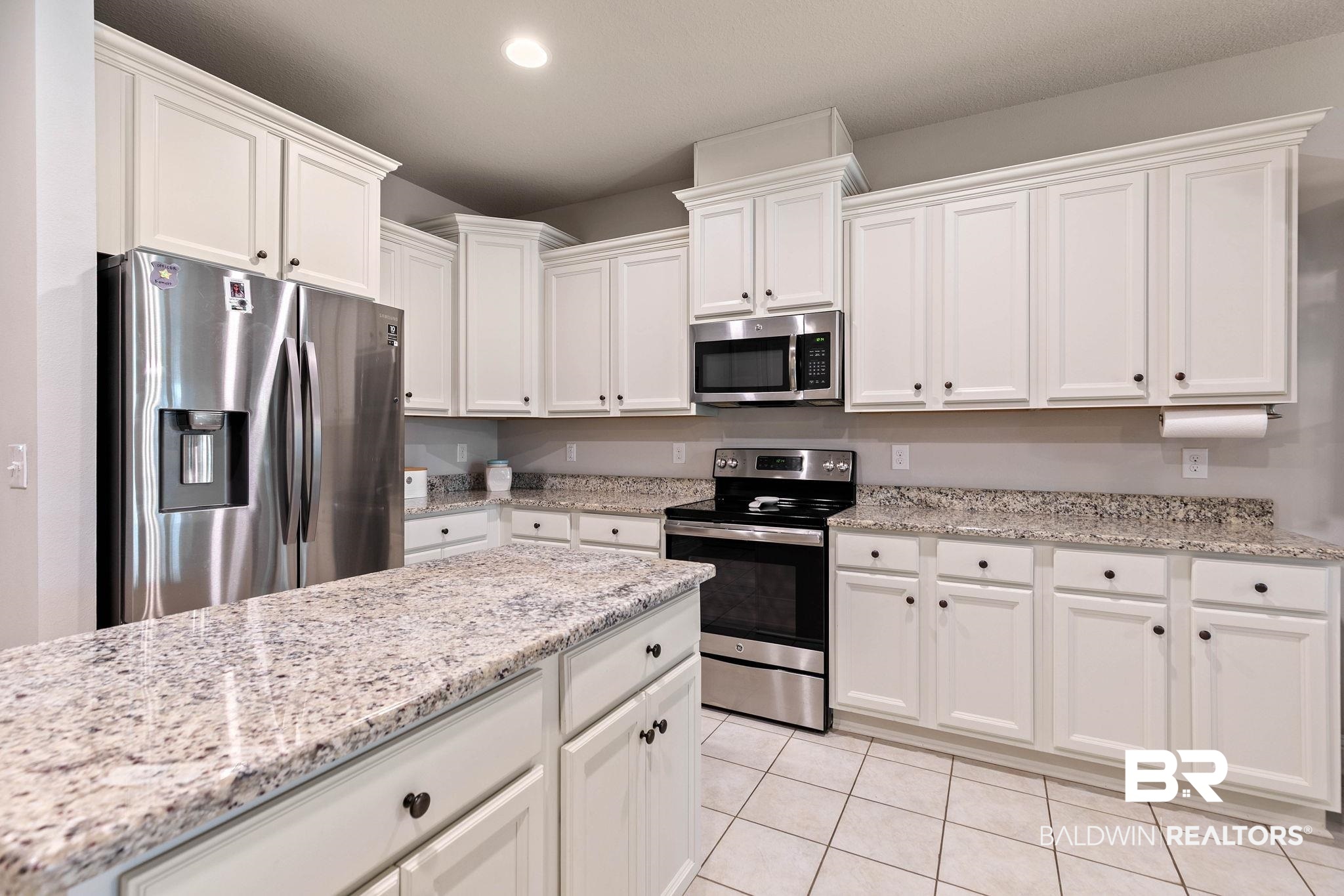 12750 B Jenkins Pit Road Daphne, AL 36527 - Photo 23 of 89 Kitchen featuring stainless steel appliances, white cabinets, light stone countertops, and light tile patterned floors