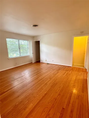 a view of a hallway with wooden floor and a window