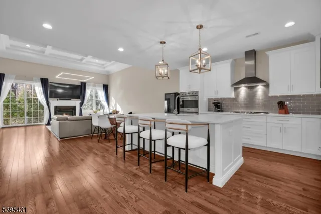 a kitchen with stainless steel appliances granite countertop a stove a sink dishwasher a refrigerator and a dining table with wooden floor