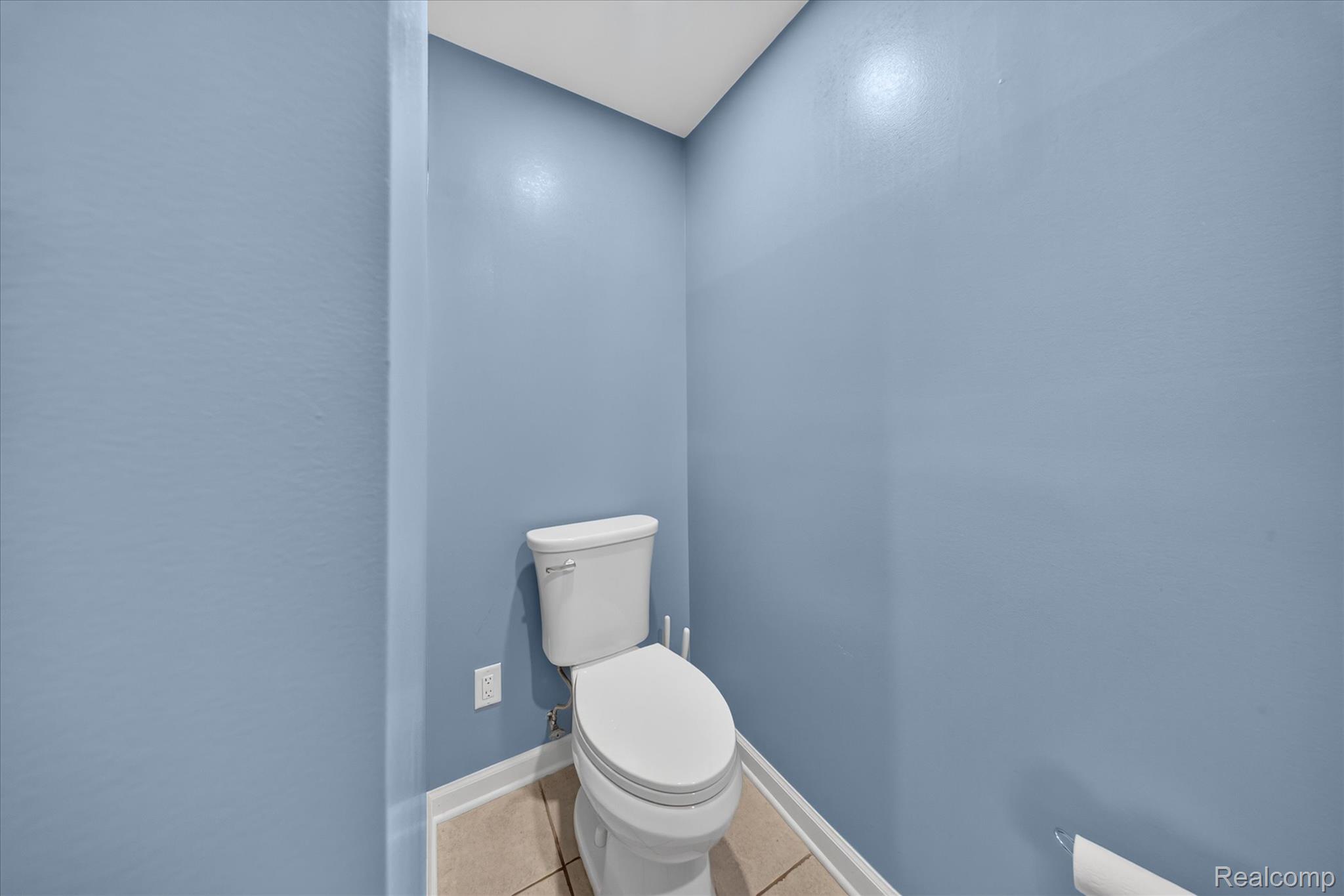 8114 Chilson Road Pinckney, MI 48169 - Photo 25 of 32 Powder room featuring a white two-piece toilet, light blue painted walls, and light-toned tile flooring