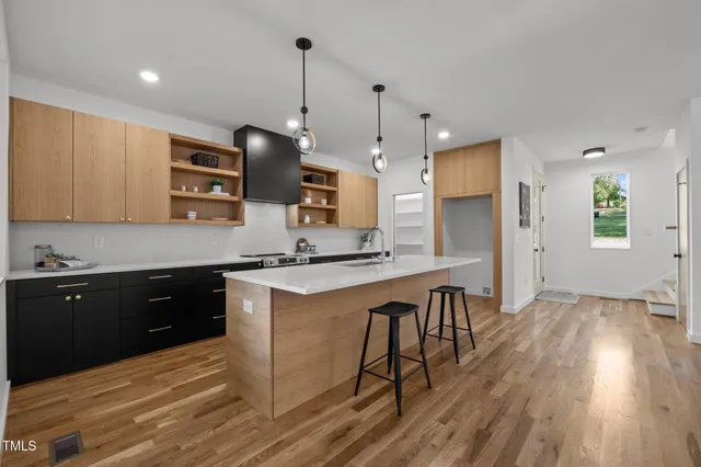 a kitchen with stainless steel appliances granite countertop wooden floors a stove and a refrigerator