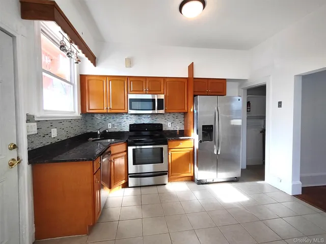 a kitchen with granite countertop a refrigerator a sink a stove and white cabinets