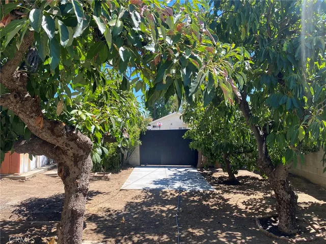 a backyard of a house with large trees and wooden fence