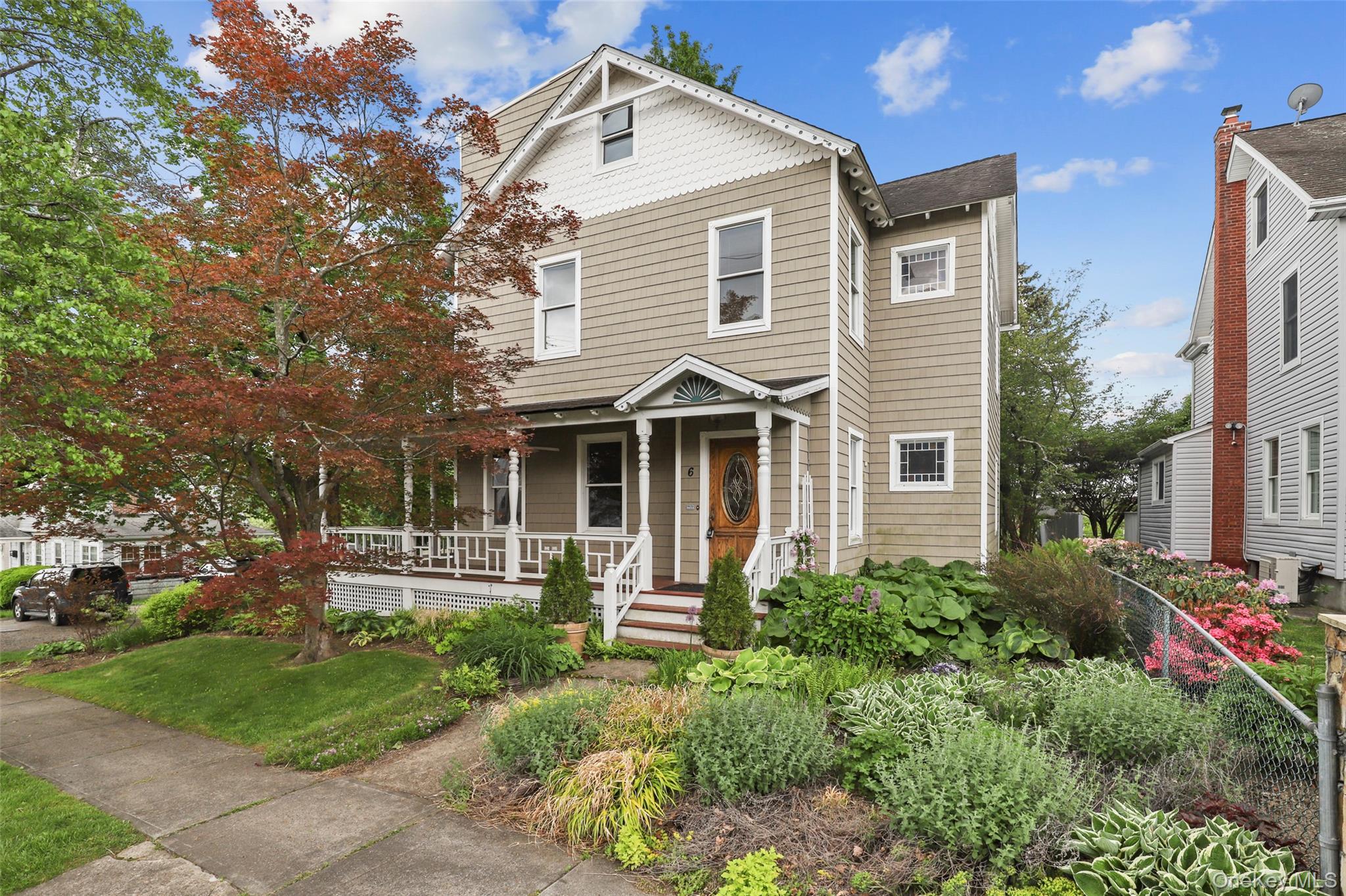 a view of a white house next to a yard with big trees