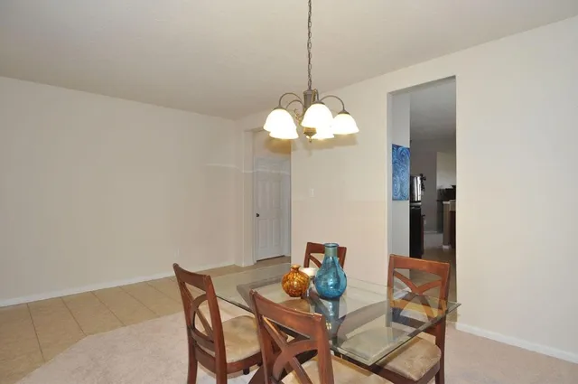 a kitchen area with stainless steel appliances kitchen island granite countertop a stove a refrigerator a dining table and chairs with wooden floor