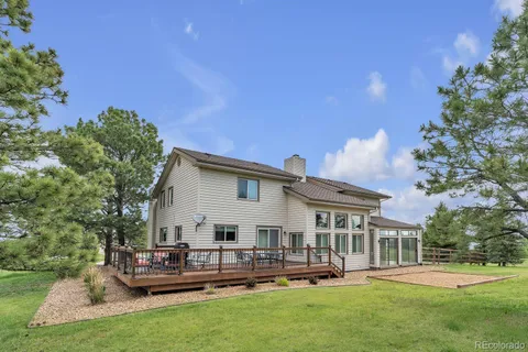 a view of house with a big yard and potted plants and large trees