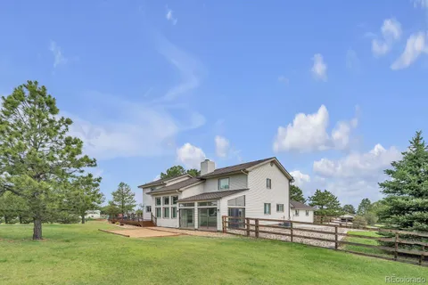 a view of a white house with a big yard and large trees
