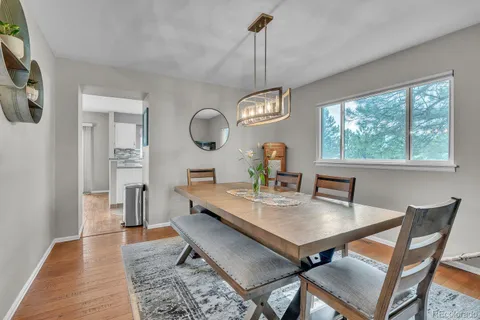 a view of a dining room and livingroom with furniture wooden floor a rug a flat screen tv a rug and a chandelier