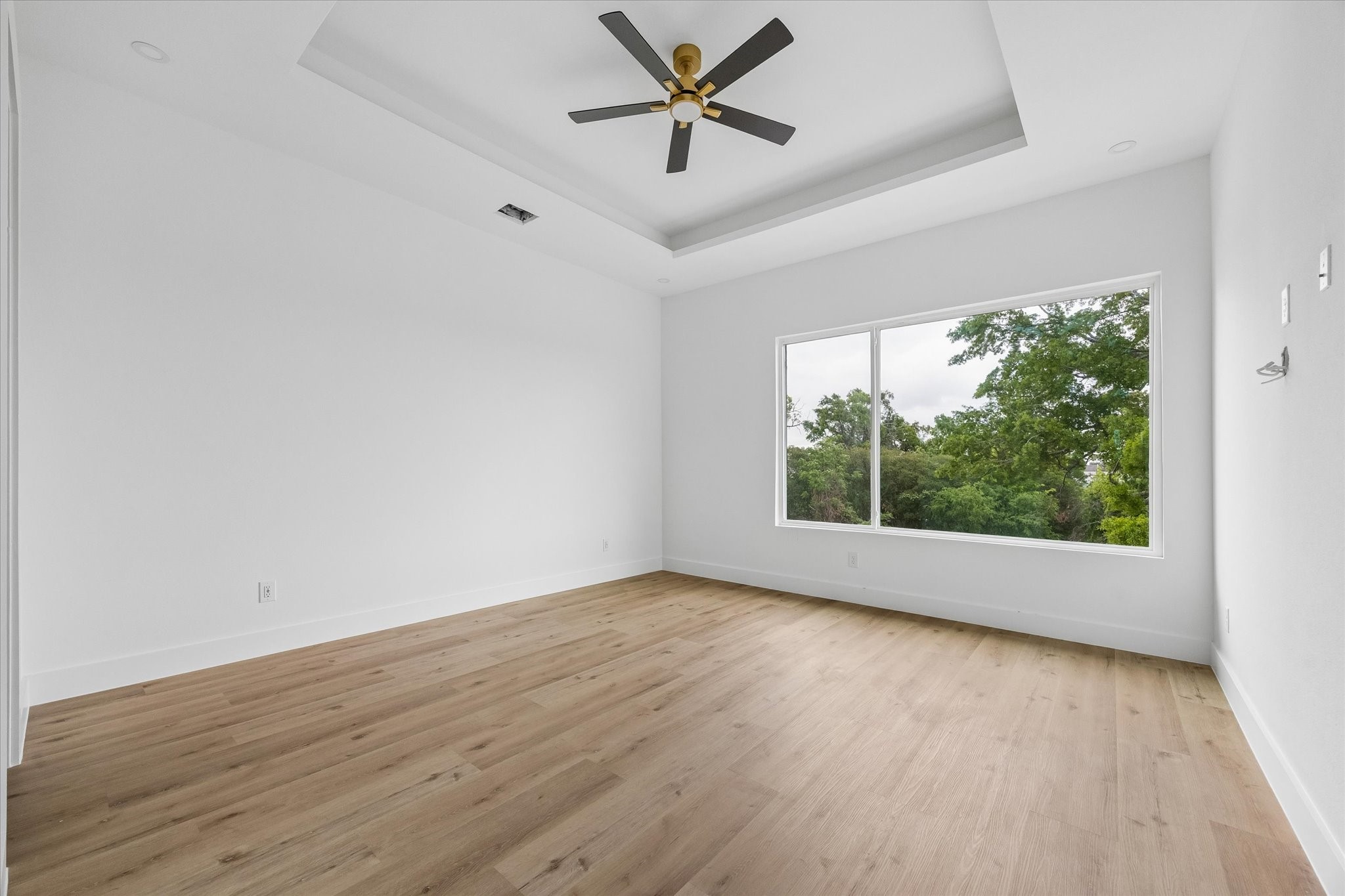 1034 West 17th Street, Unit B Houston, TX 77008 - Photo 12 of 25 Primary suite showcasing a tray ceiling, ceiling fan, two walk-in closets, and an expansive picture window.