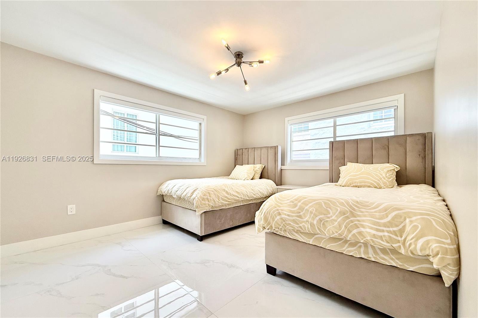 4122 Collins Avenue, Unit 2B Miami Beach, FL 33140 - Photo 5 of 13 a bedroom with two beds and a chandelier