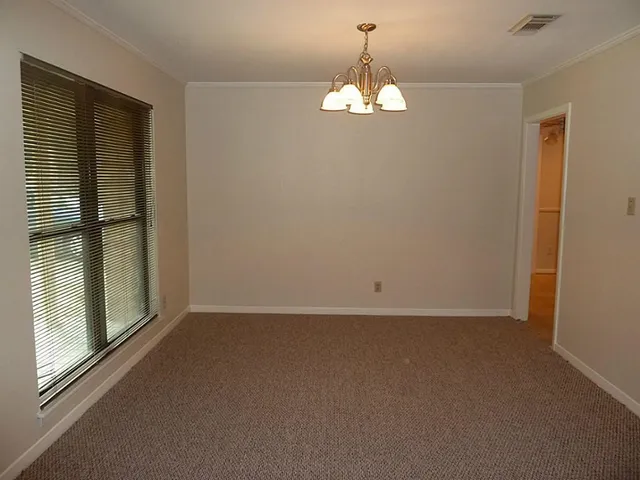 en empty room with windows and chandelier