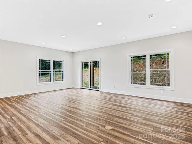 a view of an empty room with wooden floor and windows
