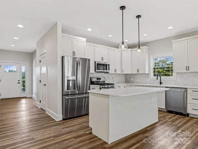 a kitchen with kitchen island white cabinets and stainless steel appliances