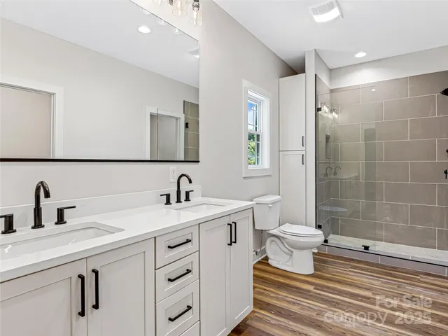 a bathroom with a double vanity sink toilet and shower