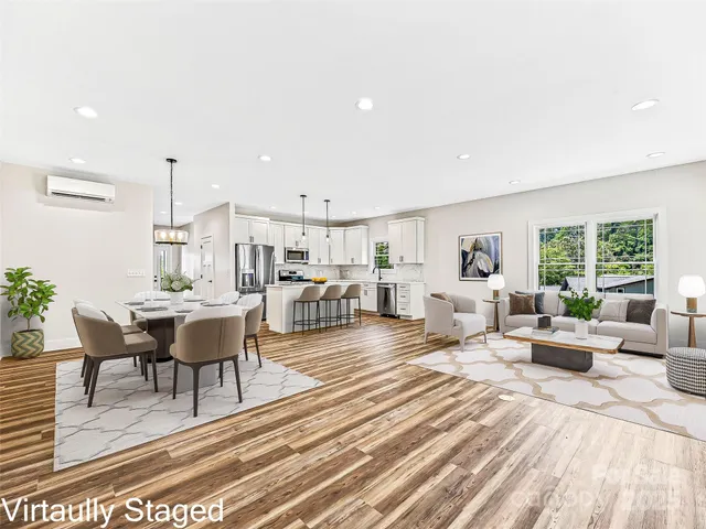 a living room with furniture wooden floor dining table and a large window