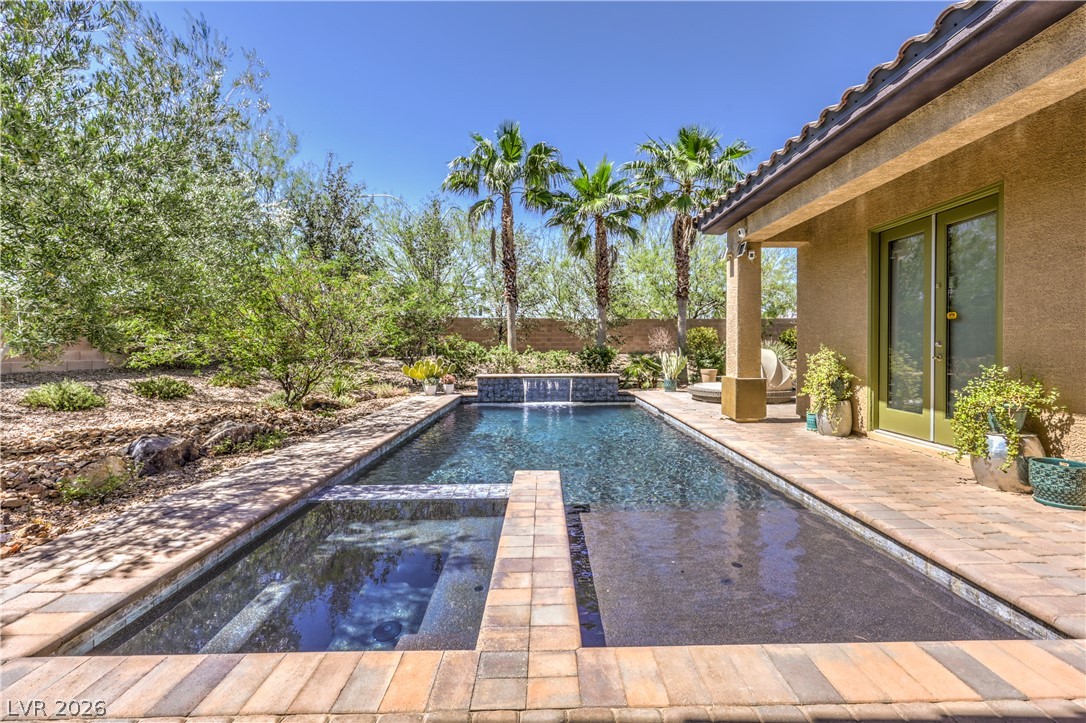 7119 Arabian Ridge Street Las Vegas, NV 89131 - Photo 46 of 73 An inviting backyard oasis awaits, featuring a refreshing in-ground pool, covered patio, and vibrant landscaping.