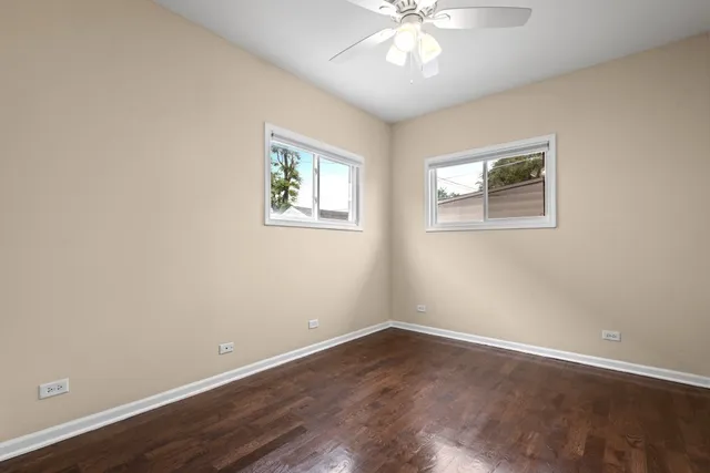 a view of an empty room with wooden floor and a chandelier fan