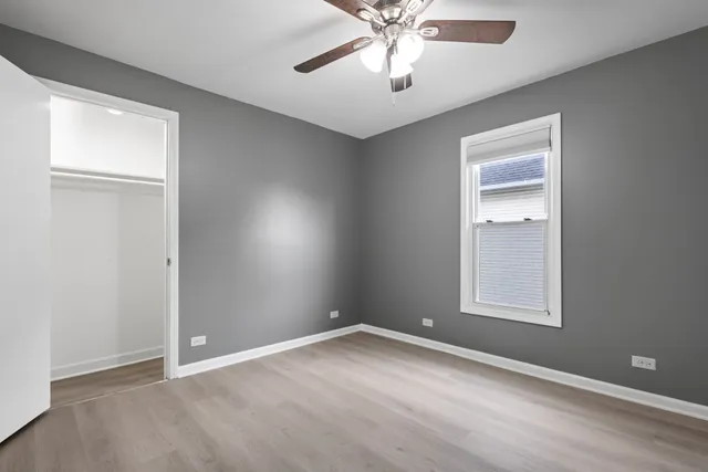 an empty room with a window and a chandelier fan