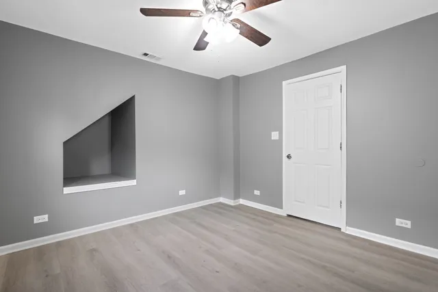 a view of an empty room with window and wooden floor