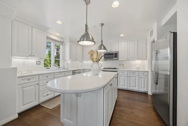 a kitchen with kitchen island granite countertop a sink a counter space appliances and cabinets