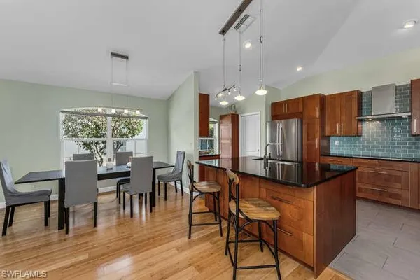 a kitchen with stainless steel appliances kitchen island granite countertop a table chairs and a refrigerator