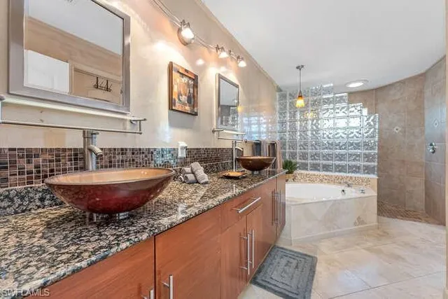 a large bathroom with a granite countertop tub a double vanity sink and mirror