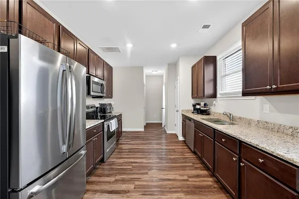 a large kitchen with stainless steel appliances granite countertop a refrigerator a stove and a sink