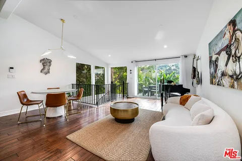 a living room with furniture a large window and wooden floor