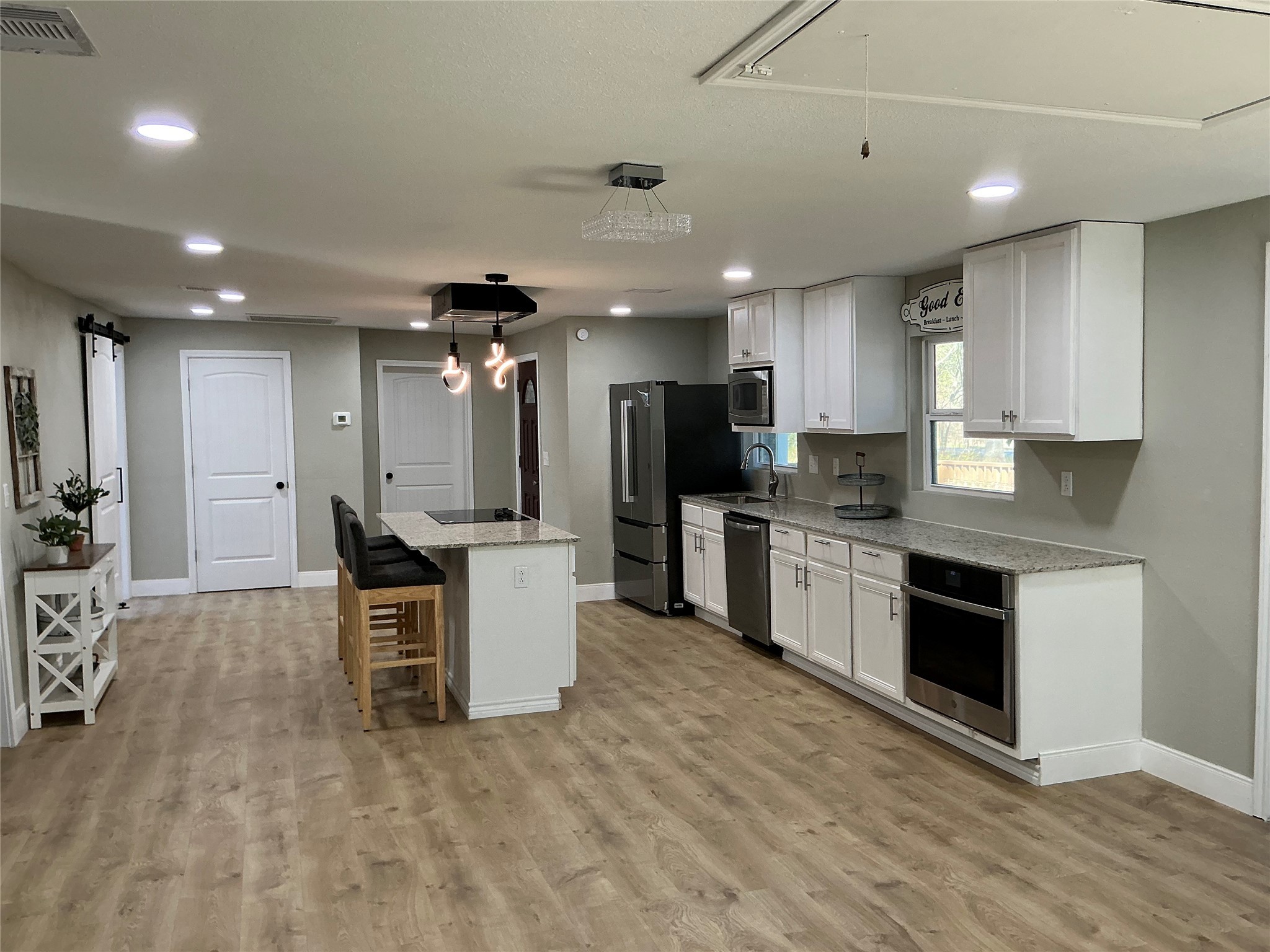 10928 L And M Road Montgomery, TX 77316 - Photo 8 of 31 a kitchen with stainless steel appliances kitchen island granite countertop a stove top oven a sink dishwasher a refrigerator and white cabinets with wooden floor