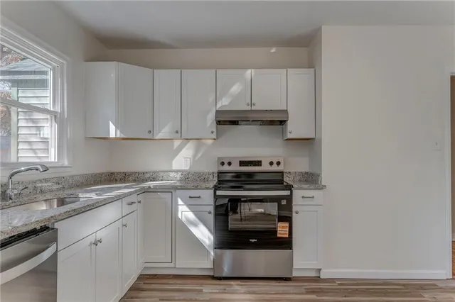a kitchen with stainless steel appliances granite countertop a stove and white cabinets