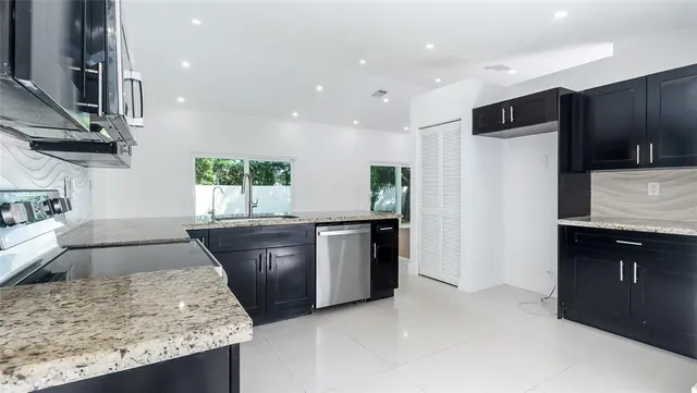 a kitchen with stainless steel appliances granite countertop wooden cabinets a sink and a oven