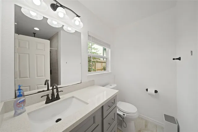 a bathroom with a sink vanity granite and toilet