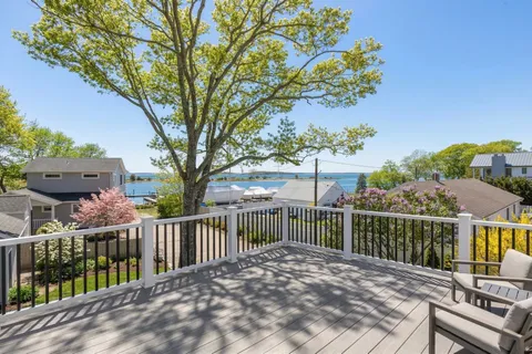 a view of a house with wooden deck in front of house