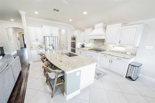 a kitchen with kitchen island granite countertop lots of white cabinets appliances and a center island