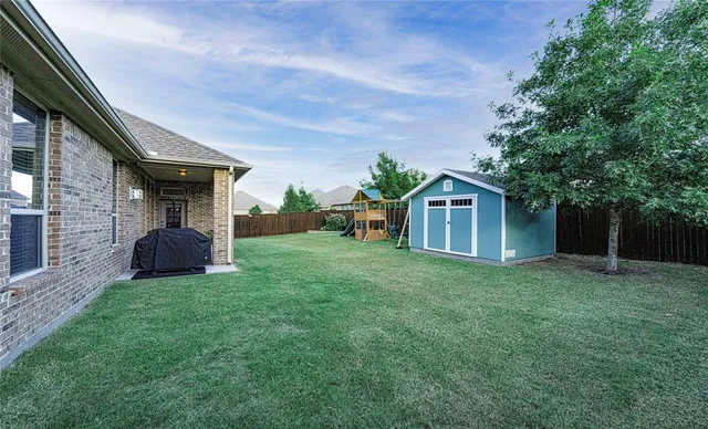 a view of a house with a yard and a large tree