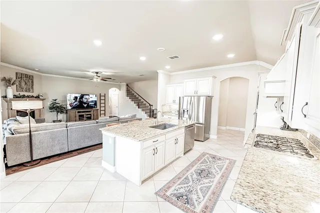 a large white kitchen with a stove a sink a refrigerator and white cabinets with wooden floor
