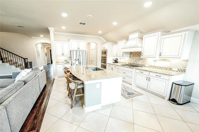 a kitchen with kitchen island granite countertop lots of white cabinets a sink and appliances