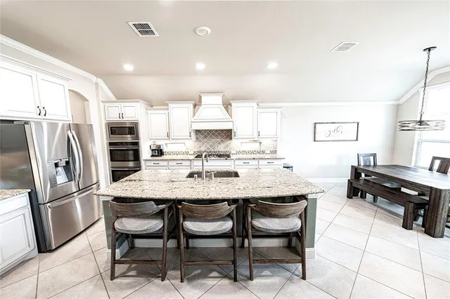 a kitchen with stainless steel appliances granite countertop a table chairs and a refrigerator