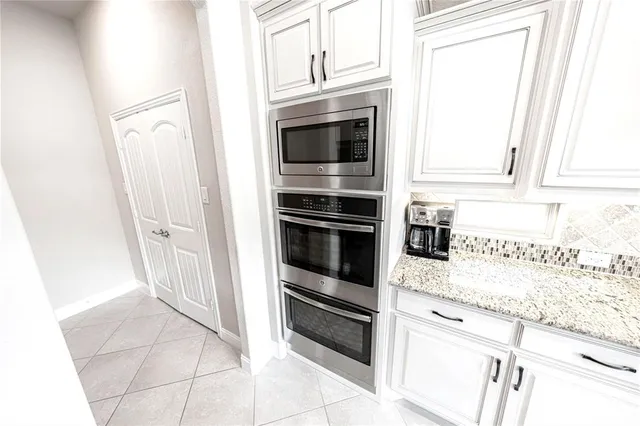 a kitchen with granite countertop white cabinets and stainless steel appliances