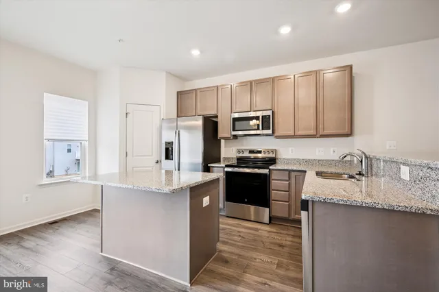 a kitchen with kitchen island granite countertop appliances cabinets and a sink